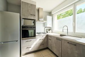 d'une cuisine équipée d'appareils en acier inoxydable et d'une fenêtre. dans l'établissement Maison Brehat - 3 chambres parking & jardin, à Saint-Jacques-de-la-Lande