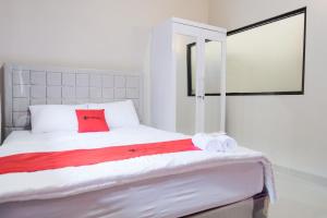 a white bed with red pillows and towels on it at RedDoorz Syariah near Hajimena Lampung in Lampung