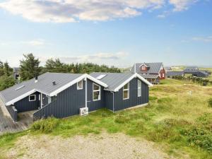 a house with black siding on a grass field at 10 person holiday home in Harboøre-By Traum in Harboør