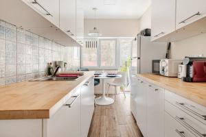 a white kitchen with a sink and a table at Refreshed apartment with private garden in Almada
