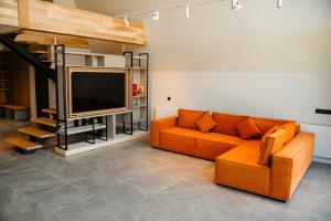 a living room with an orange couch and a television at Tihuta Chalet in Piatra Fantanele