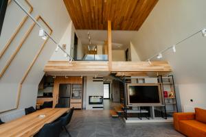an attic living room with a large tv and a couch at Tihuta Chalet in Piatra Fantanele