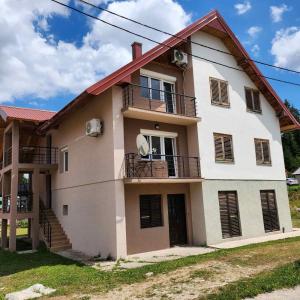 una grande casa bianca con finestre e balcone di Apartman Planinski Raj a Žabljak