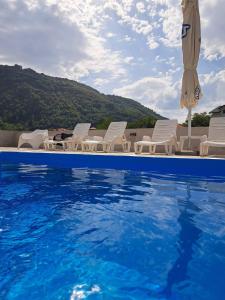 a pool with chairs and an umbrella and the water at Apartmani Sunce Stara planina in Crni Vrh