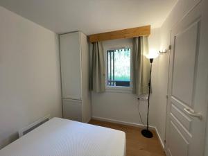 a small bedroom with a white bed and a window at Newly renovated flat on the slopes in Avoriaz