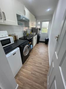 a small kitchen with a washer and dryer in it at Tranquil Thamesmead Treasure - London in Thamesmead +26 photos