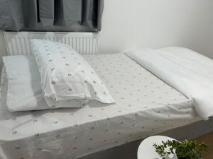 a bed with white sheets and pillows on it at Harrow Haven - Sleeps 5 & Free parking in Harrow