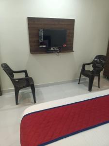 a room with two chairs and a tv on the wall at SRi NARMADA GRAND in Hanamkonda