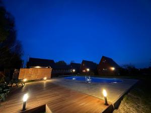 a swimming pool at night with lights on the deck at Domki KANZAS in Sławno