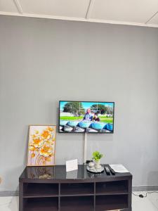 a tv on a white wall in a living room at Lilly Sky Apartments in Kitwe