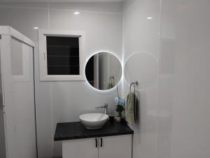 a white bathroom with a sink and a mirror at Sharnyta's Studio Aitutaki in Amuri +14 photos