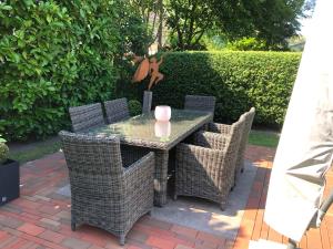a table with wicker chairs and a pink candle on it at Stilvolle 2 5 Zimmer Wohnung unter Reet in SPO mit Garten in Sankt Peter-Ording