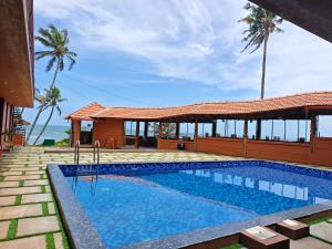 a swimming pool in front of a villa at Bella Casa Beach Resort in Varkala