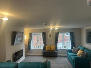 a living room with two blue couches and a tv at 3 bed flat 10 mins to Alton Towers Sleeps 6-8 people in Cheadle