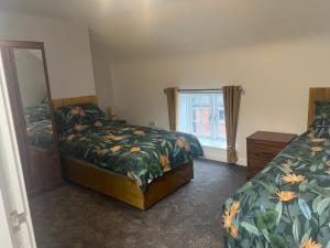 a bedroom with two beds and a mirror and a window at 3 bed flat 10 mins to Alton Towers Sleeps 6-8 people in Cheadle