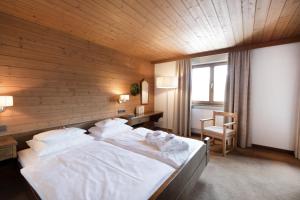 a bedroom with a large white bed with a wooden wall at Krone Hittisau - Hotel & Restaurant im Bregenzerwald in Hittisau