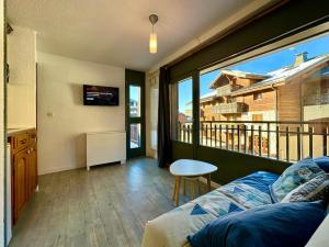 Una sala de estar con un sofá y una ventana grande. en Edelweiss Résidence plein centre de la station rez de chaussée 50 m des navettes gratuites belle terrasse et grand parking privé en sous sol, en Les Carroz d'Araches