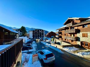 Un coche aparcado en una calle con edificios cubiertos de nieve. en Edelweiss Résidence plein centre de la station rez de chaussée 50 m des navettes gratuites belle terrasse et grand parking privé en sous sol, en Les Carroz d'Araches
