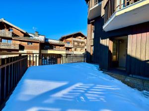 un callejón cubierto de nieve con edificios y una valla en Edelweiss Résidence plein centre de la station rez de chaussée 50 m des navettes gratuites belle terrasse et grand parking privé en sous sol, en Les Carroz d'Araches
