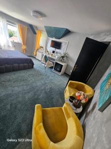 Un dormitorio con una cama y una silla amarilla. en Mera Holiday Inn, en Albeştii Pămînteni