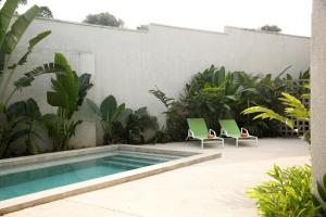 a swimming pool with two green chairs next to a building at Innoplaza Cocody in Abidjan