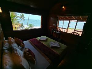 a bedroom with a bed with a view of the ocean at Bella Casa Beach Resort in Varkala