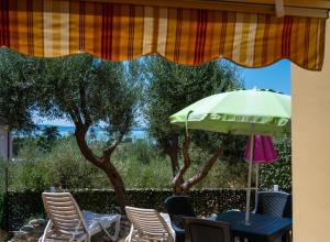 a table and chairs with a green umbrella and trees at La Casa Sul Lago - SlowLife in Passignano sul Trasimeno