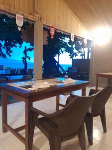a wooden table and chairs with a view of the ocean at Mikha Homestay BUNAKEN in Manado