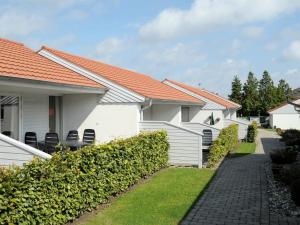 a row of white houses with chairs in a yard at 4 person holiday home in Ærøskøbing in Ærøskøbing