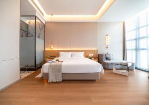 a bedroom with a large white bed and a chair at Chongqing Jinchuan Hotel in Chongqing