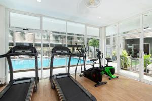 a gym with three treadmills and a swimming pool at Diya Hotel Bangkok in Amphoe Phra Khanong