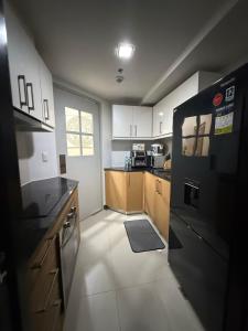 a kitchen with white cabinets and a black refrigerator at Executive Suites 4 Bedroom Condo Uptown Parksuites Bgc in Manila