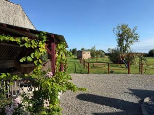a barn covered in ivy with a playground in the background at La Roulotte de Ville Chérel in Pontorson +5 photos