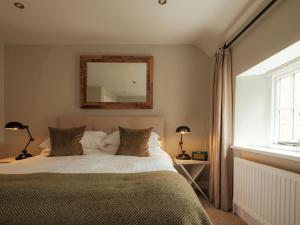 a bedroom with a bed with a mirror on the wall at The New Inn in Coln Saint Aldwyn