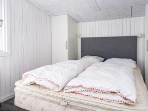 a bed with white sheets and pillows on it at 4 star holiday home in Ringkøbing in Ringkøbing