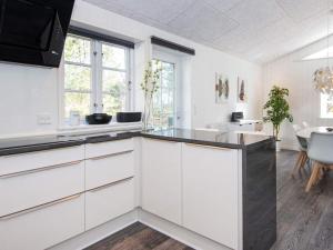 a kitchen with white cabinets and a dining room at 4 star holiday home in Ringkøbing in Ringkøbing