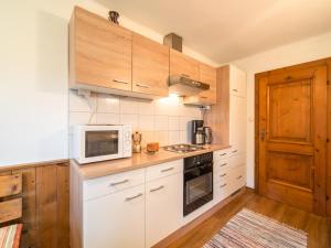 a kitchen with white appliances and wooden cabinets at Chalet in Kalchberg near Klippitztörl Ski in Bad Sankt Leonhard im Lavanttal