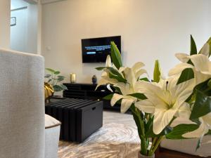 a living room with a tv and a vase with flowers at Sinza Hiddenout in Dar es Salaam