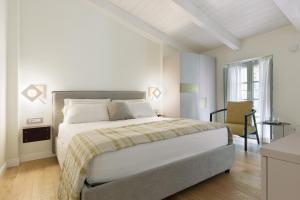 ein weißes Schlafzimmer mit einem großen Bett und einem Stuhl in der Unterkunft Cuna Milano in Mailand