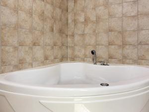 a white bath tub in a tiled bathroom at Tranquil Retreat near Golf - By Traum Ferienwohnungen in Bunken