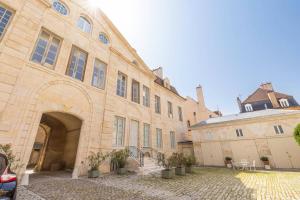 a large stone building with an archway in a courtyard at Le Sassenay in Dijon