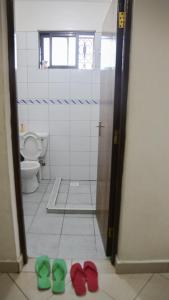 a bathroom with a toilet and green shoes on the floor at Truthvacay in Mombasa