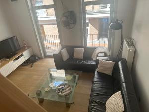 a living room with a leather couch and a glass table at Casa Le Roy in Blankenberge