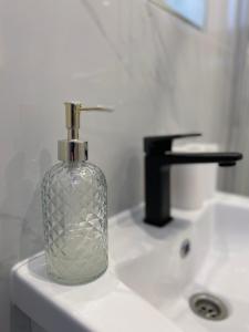 a glass bottle sitting on top of a bathroom sink at Apartament 13 z Balkonem, Centrum Grzybowo - Nadmorska 26 in Grzybowo