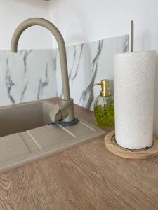 a sink with a faucet and a roll of paper towels at Apartament 13 z Balkonem, Centrum Grzybowo - Nadmorska 26 in Grzybowo