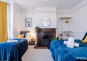 two beds in a room with a fireplace at 5BR House, Sleeps 10 guests - Free Parking - Great for Professionals & Contractors in Pontefract
