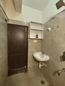 a bathroom with a sink and a black door at Luxurious 3BHK AC, Peaceful location, Premium stay in Mysore