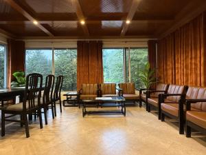 a waiting room with chairs and a table and windows at Tabash Hotel, Murree in Murree