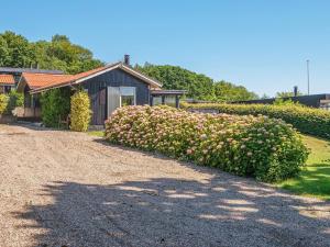 a bush with pink flowers in front of a house at 5 person holiday home in Juelsminde-By Traum in Sønderby