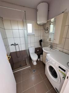 a bathroom with a toilet and a washing machine at Relax INN Sea and Olympus View in Nea Kallikrateia
